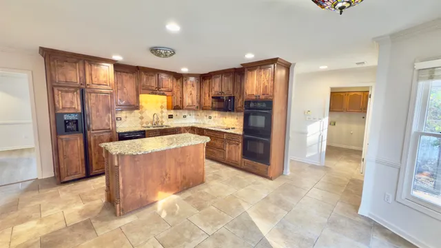 a large kitchen with stainless steel appliances kitchen island granite countertop a refrigerator and a sink
