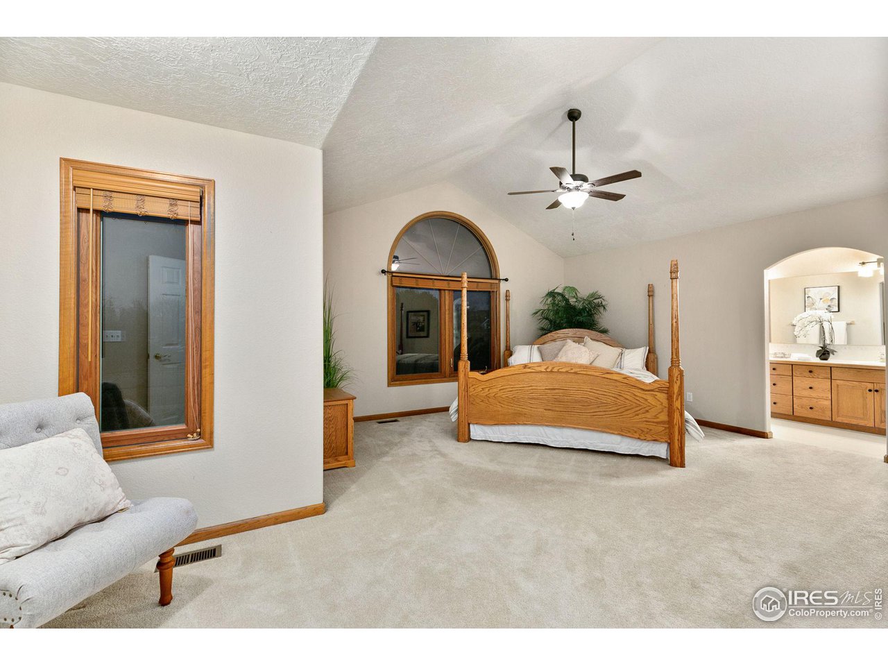 32593 Stagecoach Road Windsor, CO 80550 - Photo 21 of 28 a spacious bedroom with a bed a couch and a chandelier