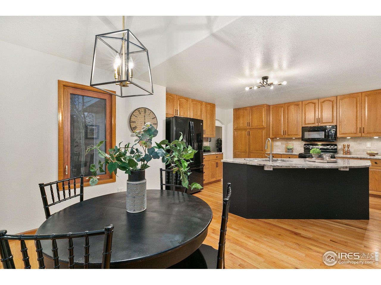 32593 Stagecoach Road Windsor, CO 80550 - Photo 5 of 28 a kitchen with kitchen island a stove a refrigerator a sink dishwasher a dining table and chairs with wooden floor