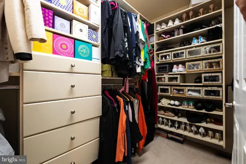 a view of walk in closet with clothes and shoes