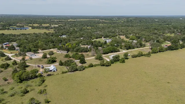an aerial view of residential houses with outdoor space and trees