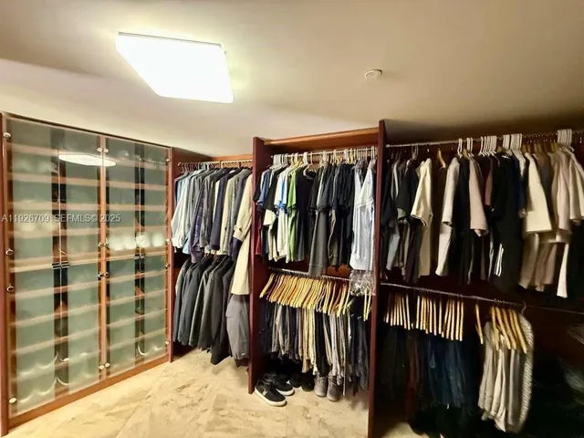 a view of walk in closet with clothes and shoes