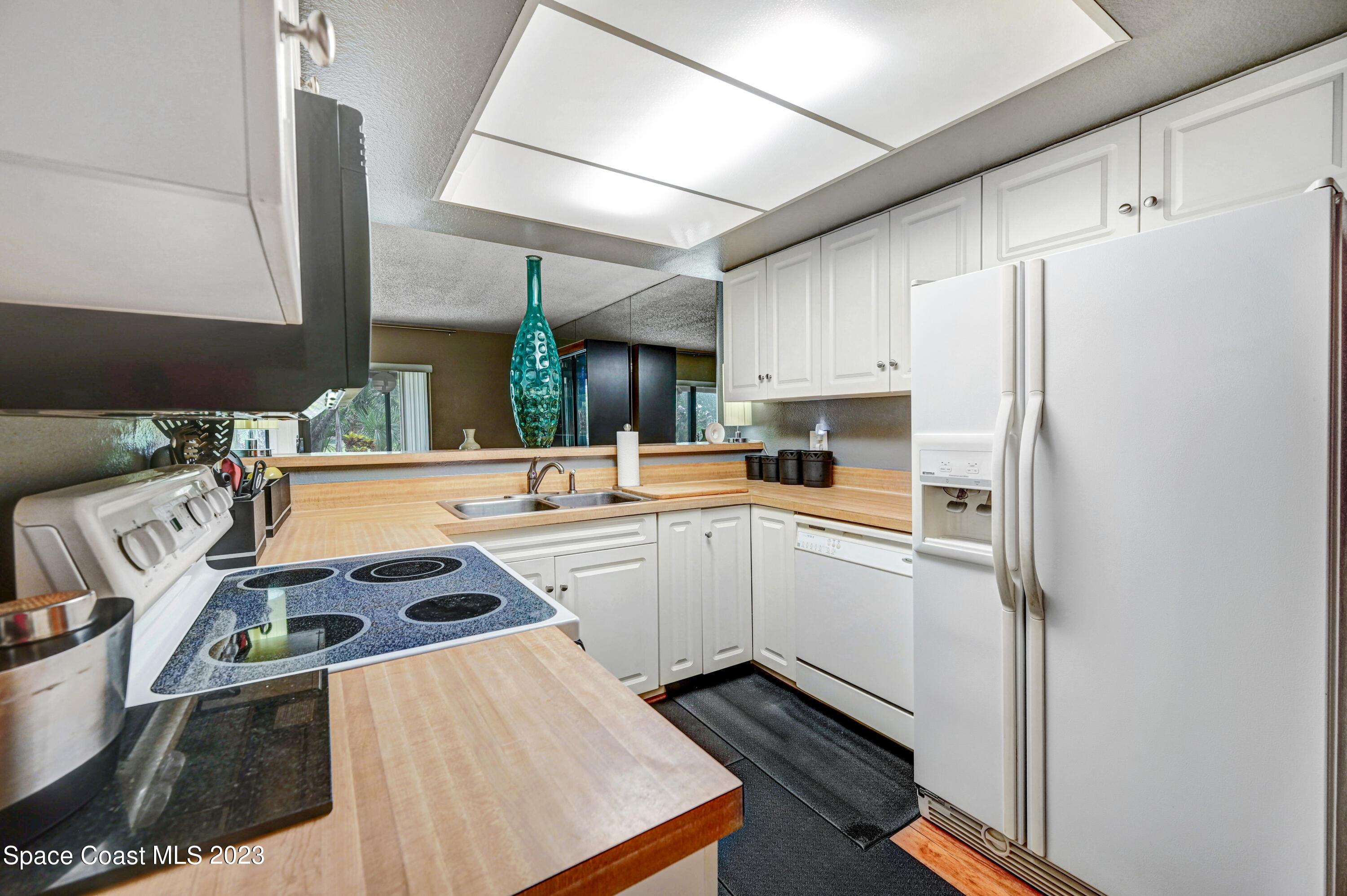 229 Augusta Way Melbourne, FL 32940 - Photo 12 of 39 a kitchen with kitchen island a stove a refrigerator and a sink with wooden floor