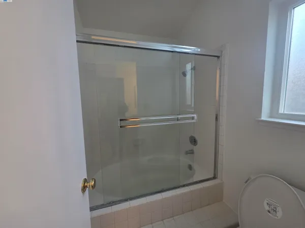 an empty room with a window and a ceiling fan