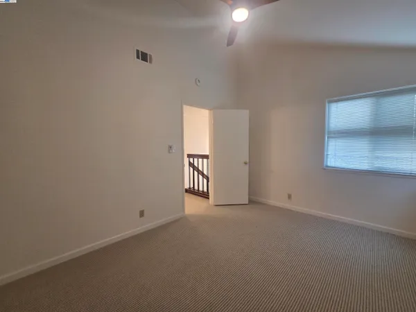 an empty room with a fan & a window