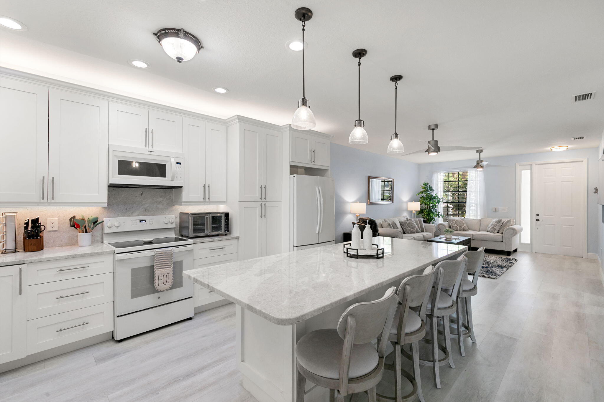 15068 Summit Pl Circle Naples, FL 34119 - Photo 7 of 29 a kitchen with stainless steel appliances kitchen island granite countertop a stove a sink a dining table and chairs with wooden floor