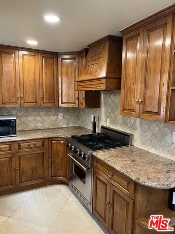 a kitchen with granite countertop wood cabinets stainless steel appliances and a sink