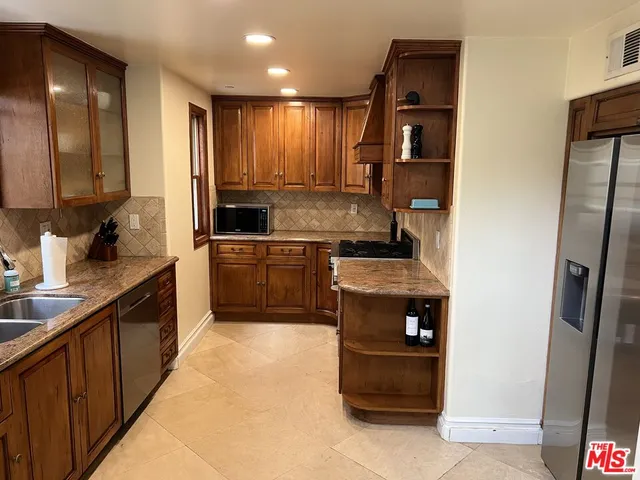 a kitchen with stainless steel appliances granite countertop a stove a sink and a refrigerator