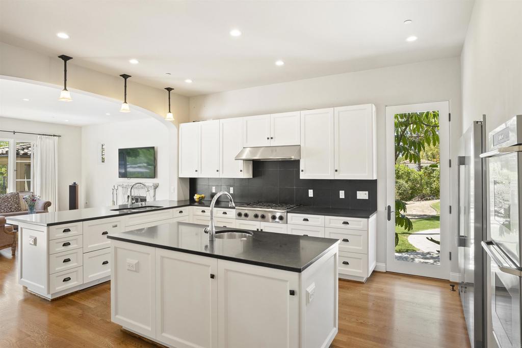 16733 Calle Hermosa San Diego, CA 92127 - Photo 15 of 43 a kitchen with stainless steel appliances white cabinets a sink a stove a refrigerator and a oven with wooden floor