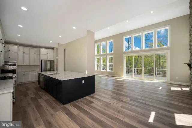 a large kitchen with granite countertop a stove a sink and white cabinets
