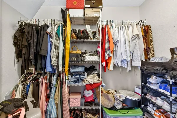 a view of walk in closet with clothes and shoes