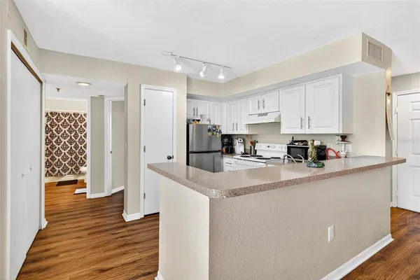 a kitchen with stainless steel appliances granite countertop a refrigerator sink and white cabinets
