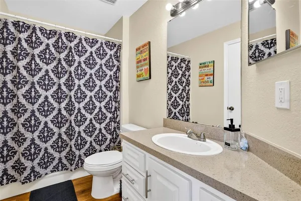 a bathroom with a granite countertop sink and a toilet