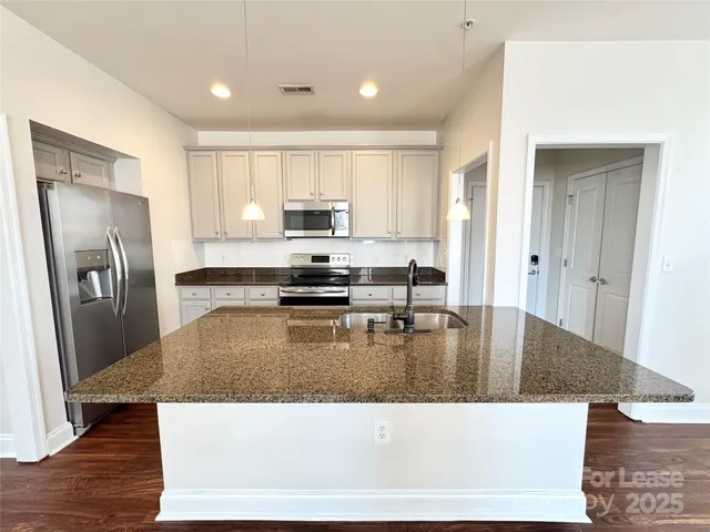 a kitchen with a refrigerator a stove a sink a counter top space and cabinets
