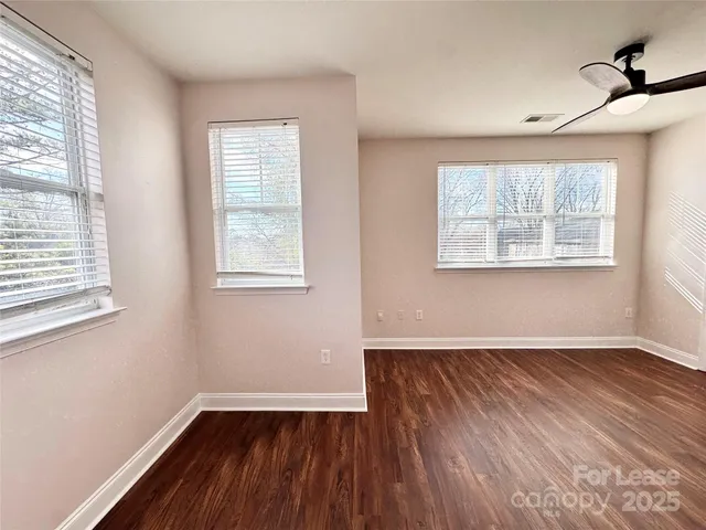a view of empty room with wooden floor and fan