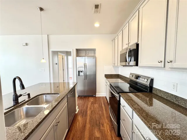 a kitchen with stainless steel appliances granite countertop a sink a stove and a wooden floors