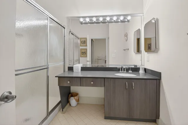a bathroom with a granite countertop sink a mirror and shower
