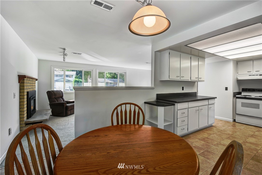 22119 Meridian Avenue South Bothell, WA 98021 - Photo 11 of 17 a kitchen with stainless steel appliances granite countertop a stove top oven a sink a dining table and chairs with wooden floor
