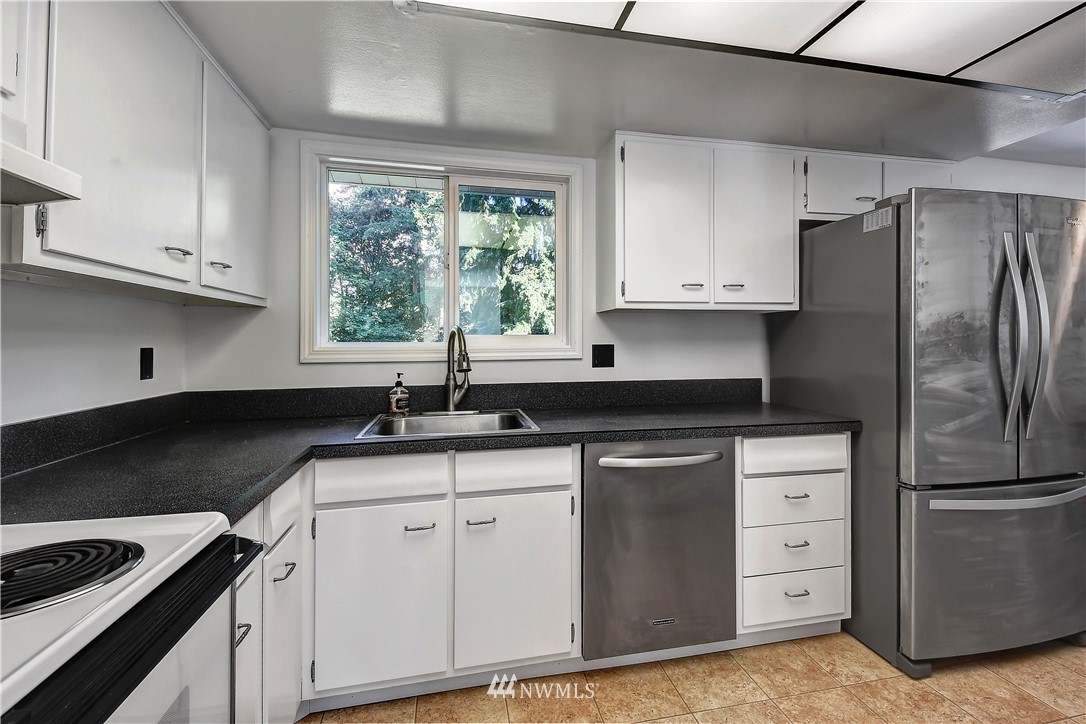 22119 Meridian Avenue South Bothell, WA 98021 - Photo 10 of 17 a kitchen with granite countertop a sink cabinets and stainless steel appliances