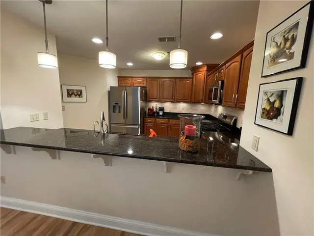 a kitchen with stainless steel appliances granite countertop a sink refrigerator and cabinets