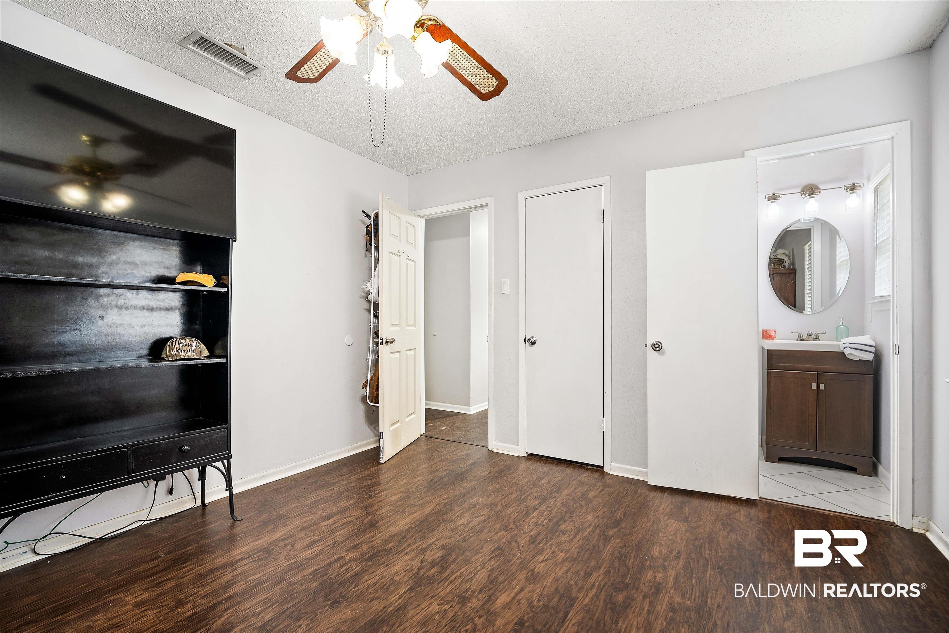 5110 Wilmer Road Wilmer, AL 36587 - Photo 13 of 24 Bedroom with ensuite bathroom, a textured ceiling, ceiling fan, sink, and wood-type flooring