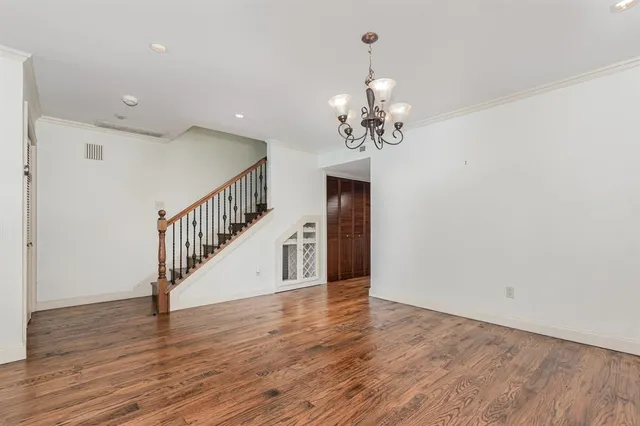 a view of an empty room with wooden floor and stairs