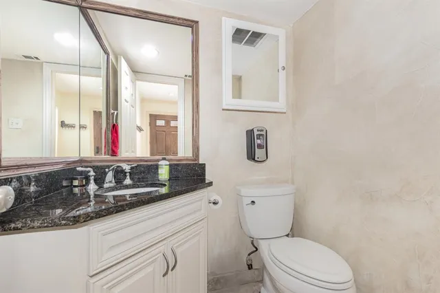 a bathroom with a granite countertop toilet sink and mirror
