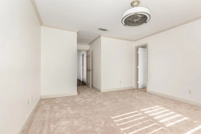 a view of an empty room with a chandelier fan