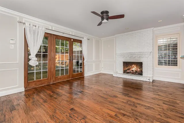 a view of an empty room with wooden floor fireplace and a window