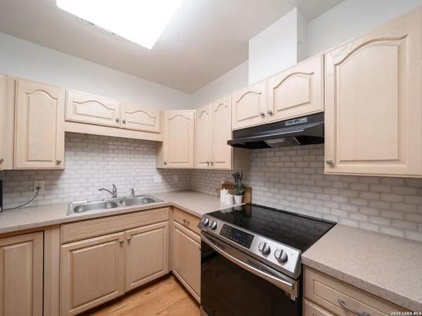 a white kitchen with granite countertop a sink a stove and cabinets