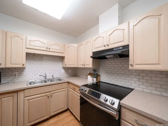 a white kitchen with granite countertop a sink a stove and cabinets