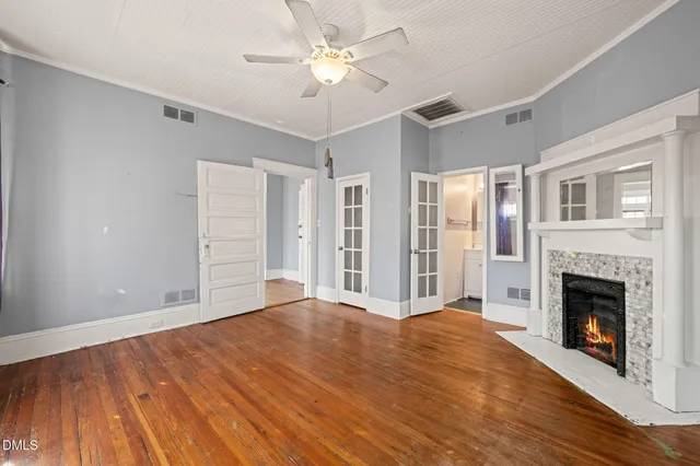 a view of an empty room with chandelier fan and fire place