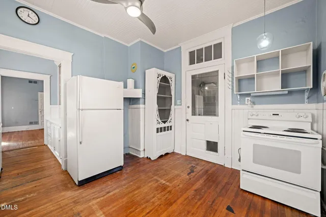 a kitchen with a refrigerator a stove top oven and a wooden floor