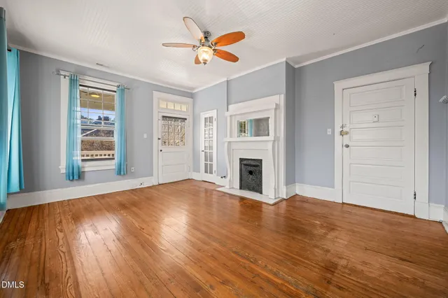 a view of an empty room with wooden floor and a window