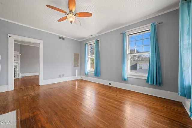 a view of an empty room with window and wooden floor