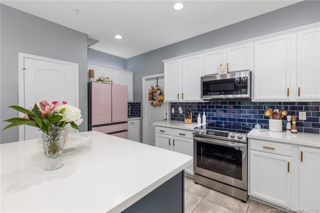 9574 Southwest Purple Martin Way Stuart, FL 34997 - Photo 11 of 32 a kitchen with stainless steel appliances a sink dishwasher stove refrigerator and microwave