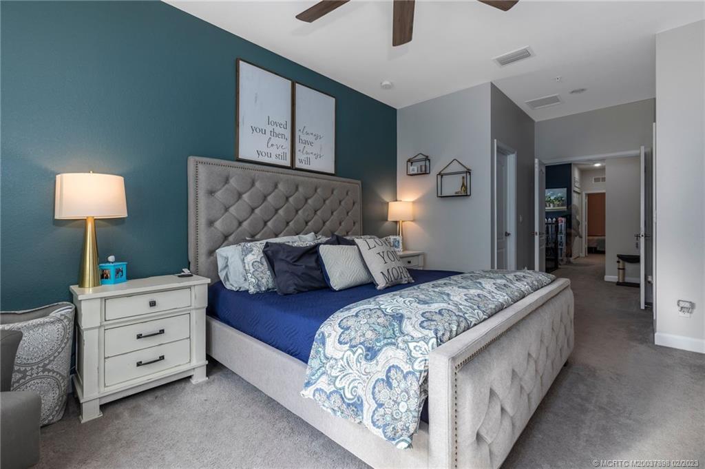 9574 Southwest Purple Martin Way Stuart, FL 34997 - Photo 13 of 32 a bedroom with a bed and a lamp