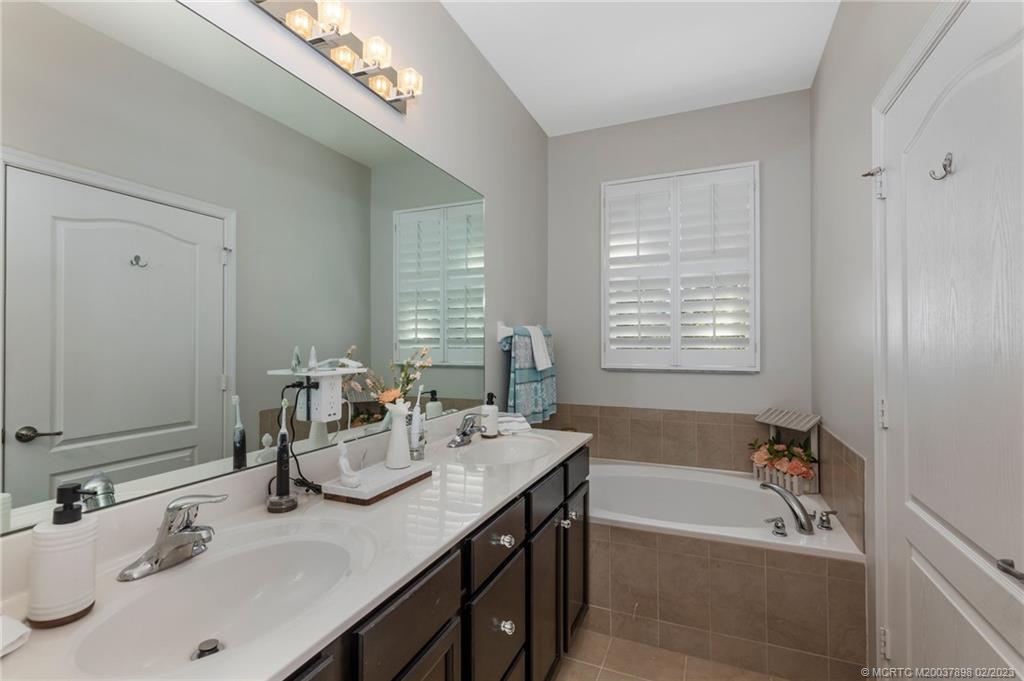 9574 Southwest Purple Martin Way Stuart, FL 34997 - Photo 15 of 32 a bathroom with a tub a sink and a mirror