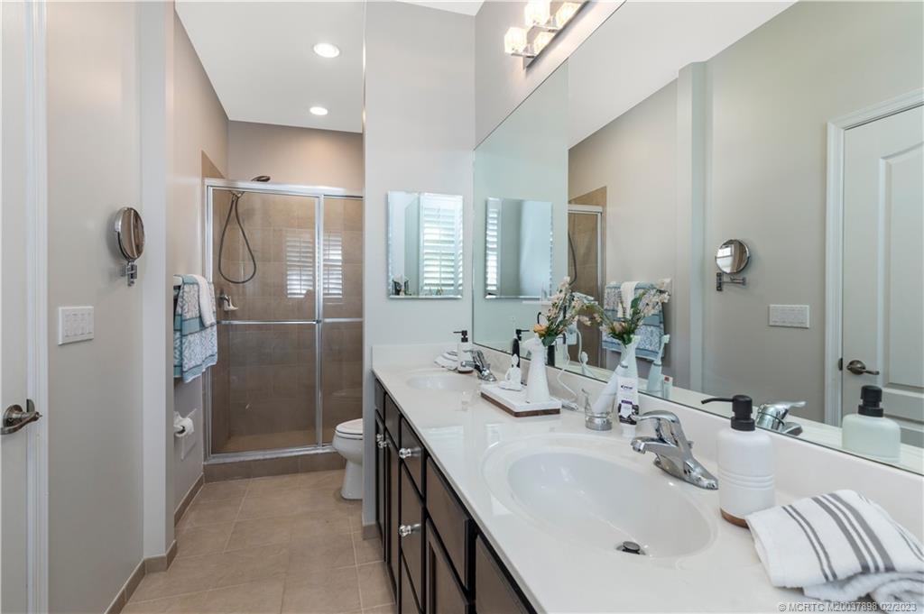 9574 Southwest Purple Martin Way Stuart, FL 34997 - Photo 16 of 32 a bathroom with a double vanity sink mirror and shower