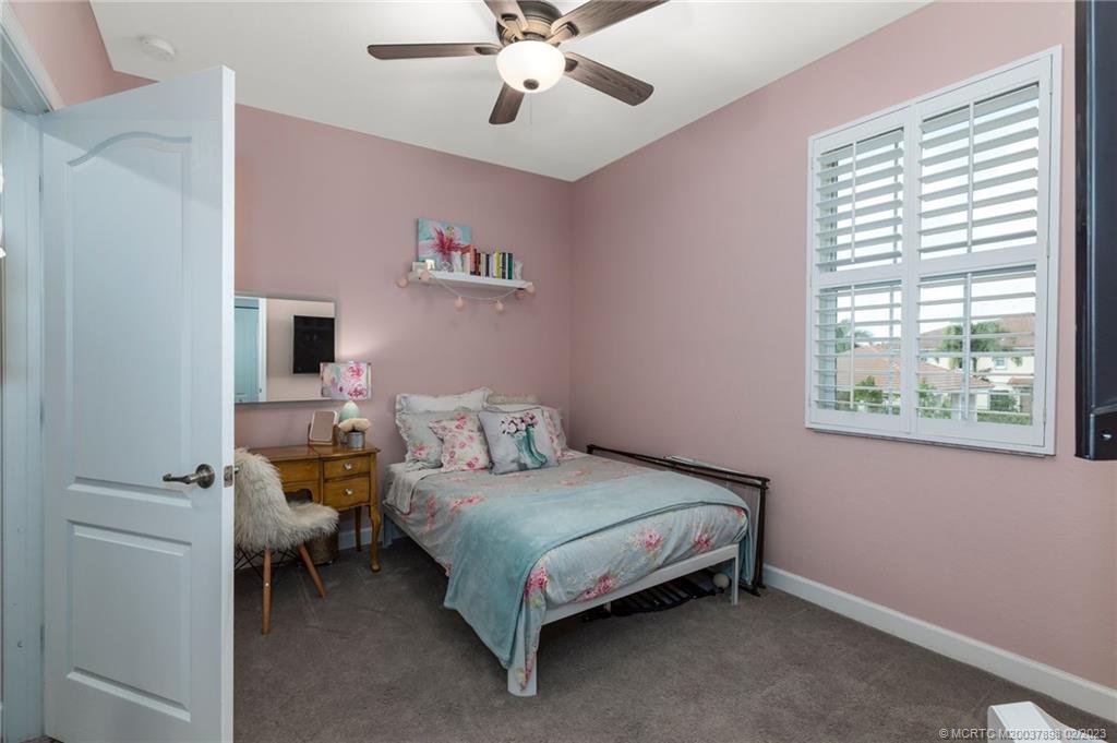 9574 Southwest Purple Martin Way Stuart, FL 34997 - Photo 19 of 32 a bedroom with a bed and a chandelier