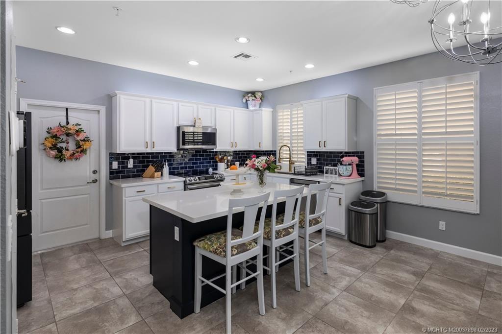 9574 Southwest Purple Martin Way Stuart, FL 34997 - Photo 7 of 32 a kitchen with a dining table chairs appliances and cabinets