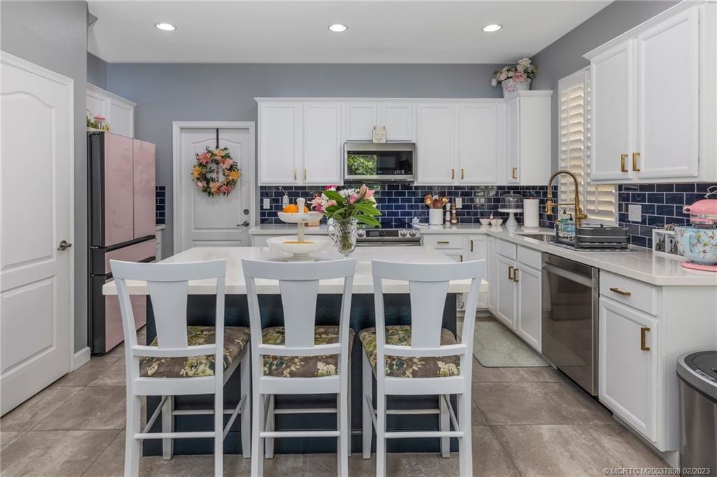 9574 Southwest Purple Martin Way Stuart, FL 34997 - Photo 8 of 32 a kitchen with a dining table chairs refrigerator and cabinets