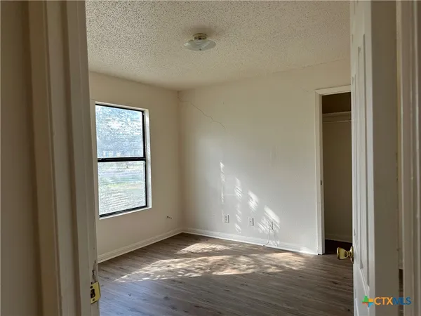 a view of empty room with window and wooden floor