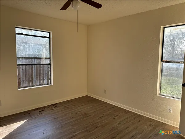 a view of an empty room with wooden floor and a window