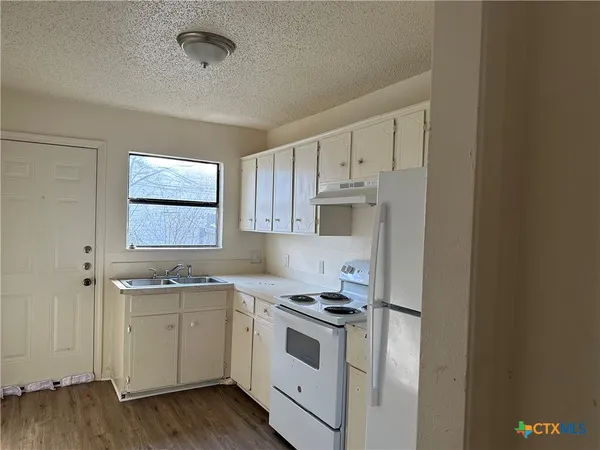 a kitchen with a sink cabinets stainless steel appliances and a window
