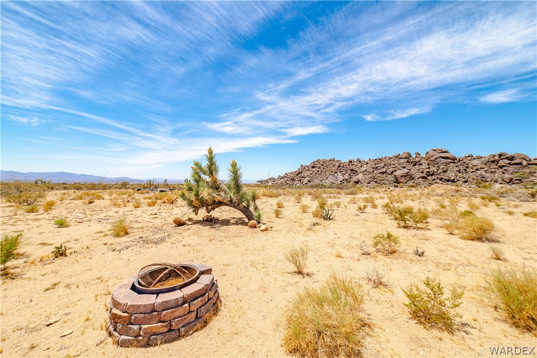 16435 South Wyatt Earp Road Yucca, AZ 86438 - Photo 35 of 57 Desert landscape featuring a stone-clad fire pit, native vegetation, and a mountainous rock formation