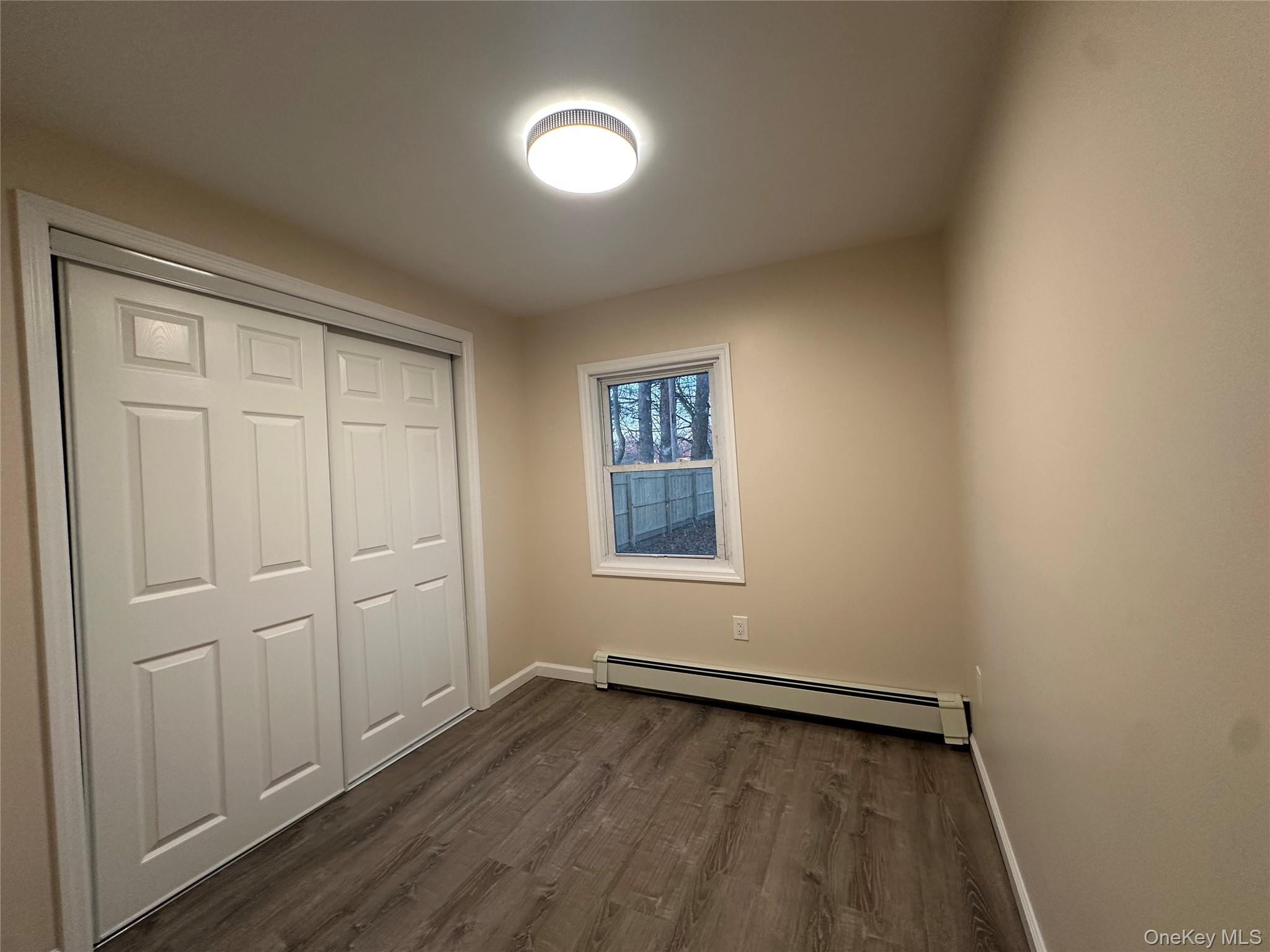 103 Sunrise Trail Wallkill, NY 12589 - Photo 15 of 24 Unfurnished bedroom with a baseboard radiator, dark wood-style floors, and a closet