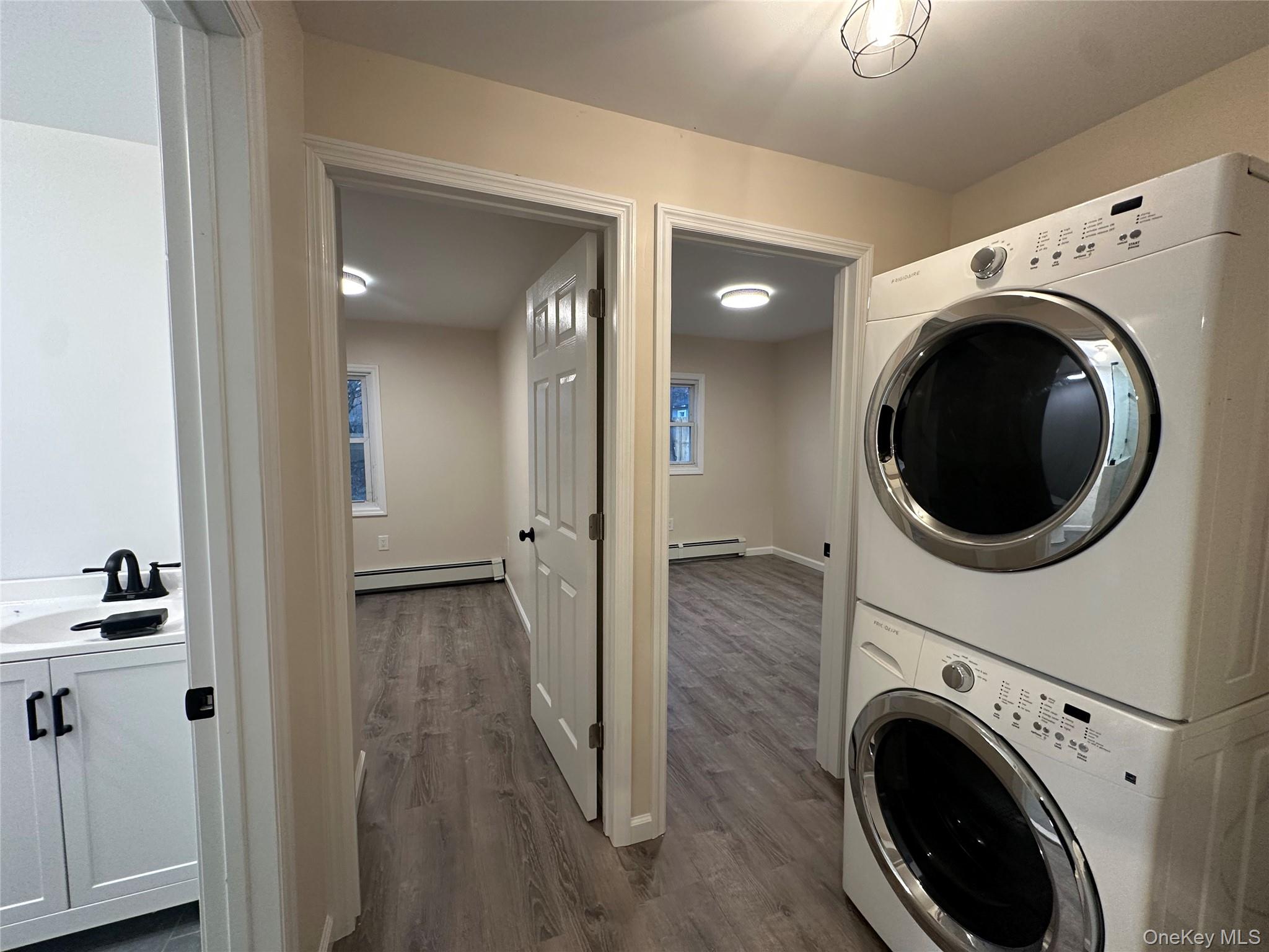 103 Sunrise Trail Wallkill, NY 12589 - Photo 21 of 24 Laundry area featuring stacked washer / drying machine, dark wood-style flooring, and a baseboard radiator