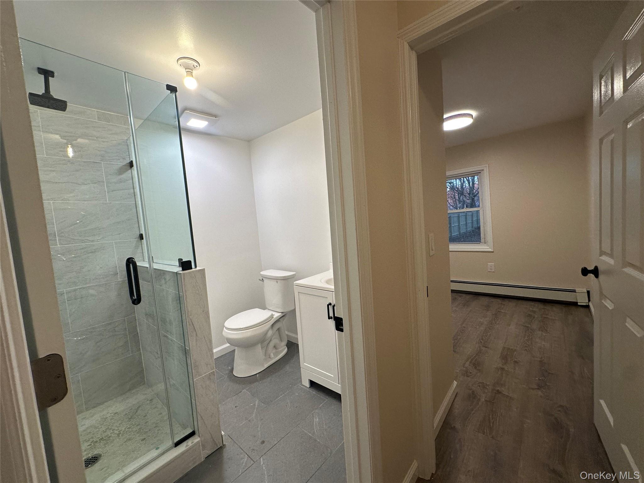 103 Sunrise Trail Wallkill, NY 12589 - Photo 22 of 24 Full bath featuring vanity, a shower stall, baseboard heating, and dark wood finished floors