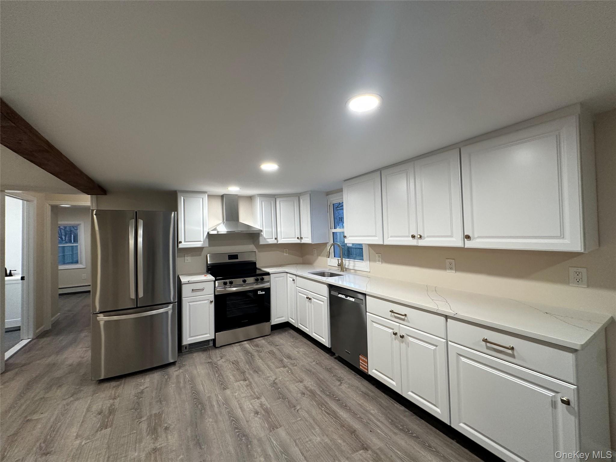 103 Sunrise Trail Wallkill, NY 12589 - Photo 9 of 24 Kitchen with appliances with stainless steel finishes, white cabinets, dark wood finished floors, wall chimney exhaust hood, and light stone counters